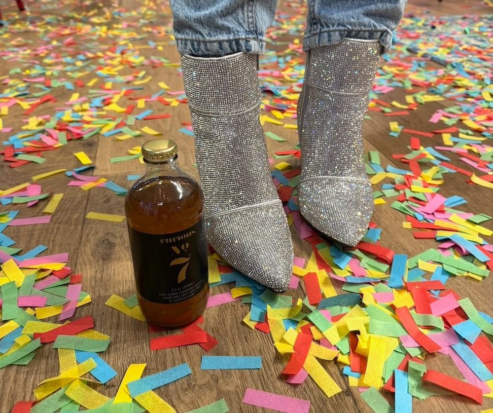Sparkly boots with confetti and a bottle of Curious No. 7
