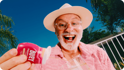 Man smiling while squeezing Digestion Drops into a glass of water. 