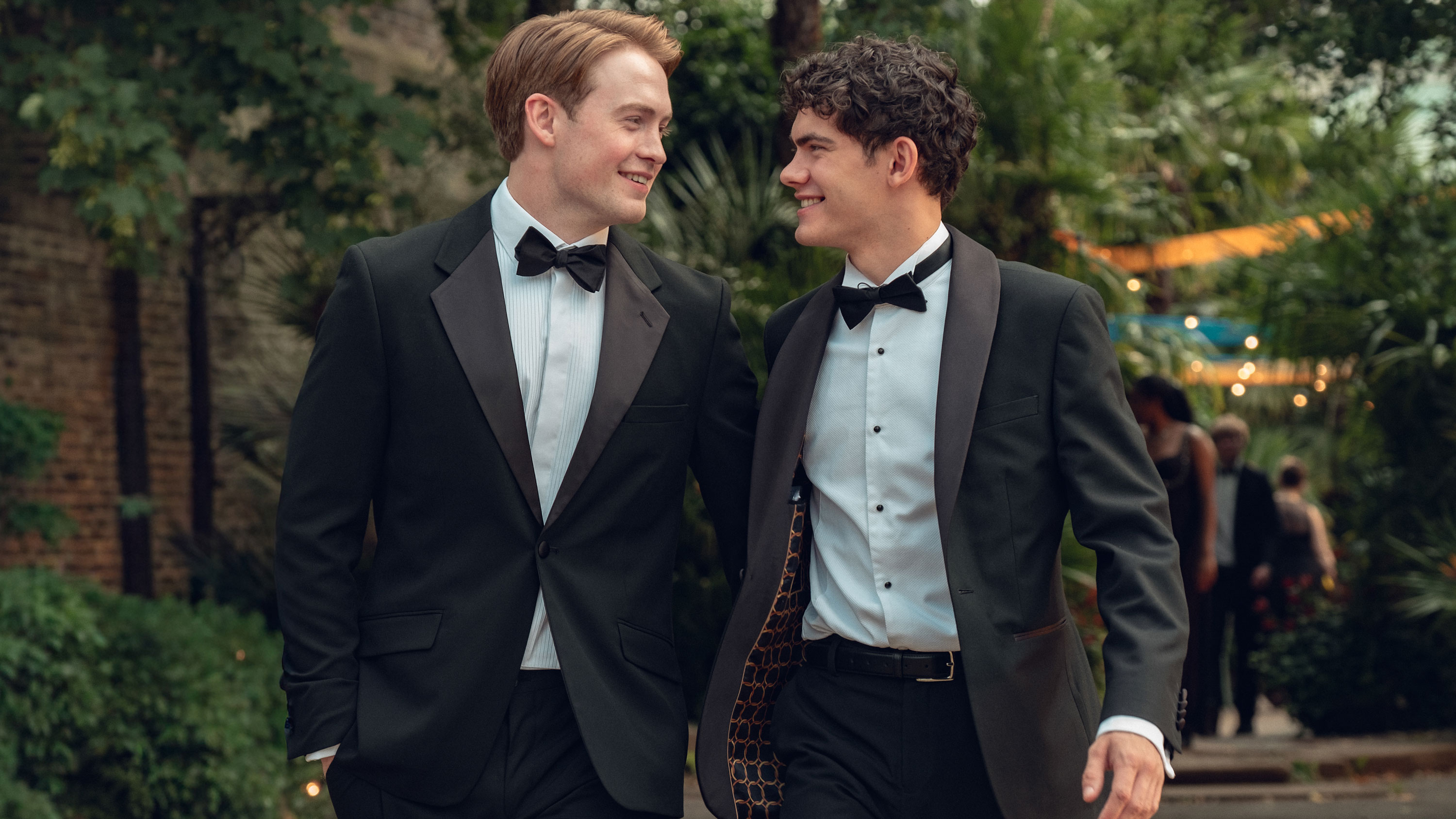 Two men look at each other smiling.