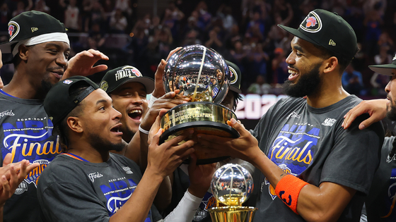 Basketball players hold a trophy in celebration.