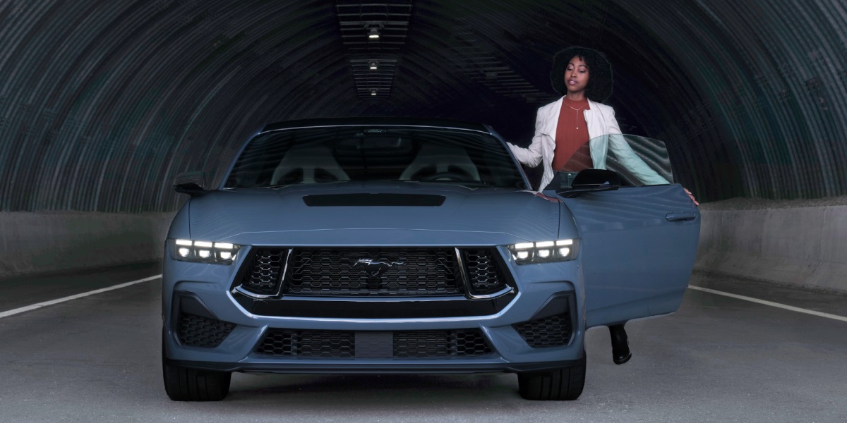 A woman standing by a blue Ford Mustang&reg; model