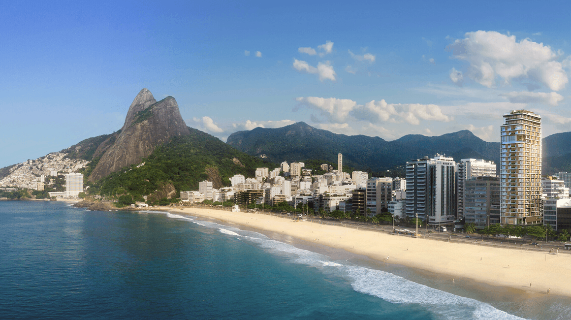 A white-sand coastline stretches into the distance, lined with buildings and a mountain range.