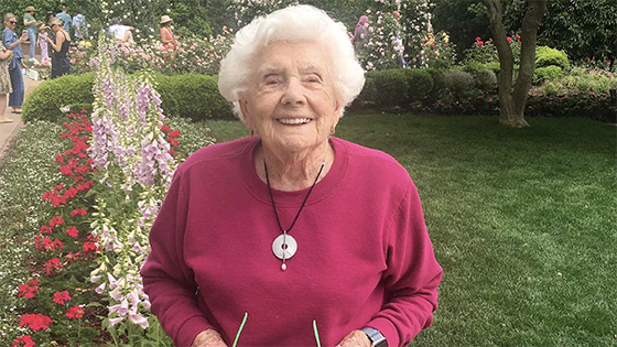 100 yr. old Joan Eichner stands in a garden.