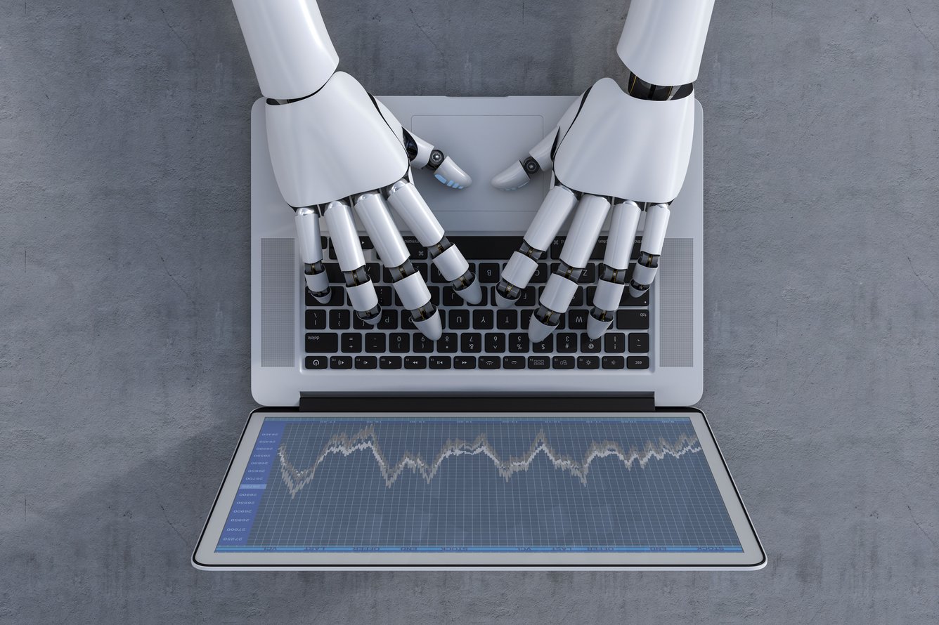 image of a white robot typing on a grey laptop computer