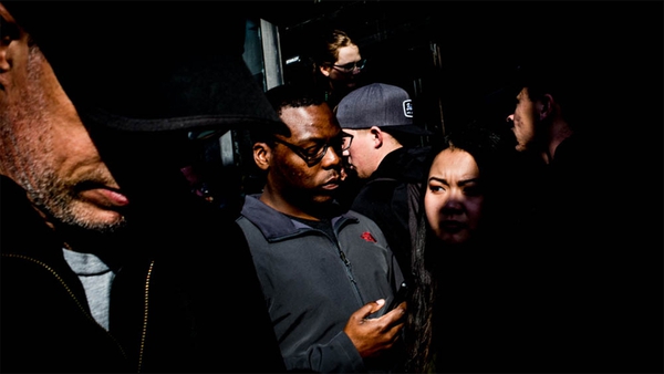 man checks his phone with crowd of people around him