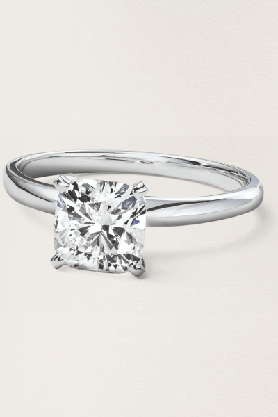 A solitaire ring with a silver band and a square cut diamond in the center.