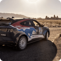 A Ford Mustang Mach‑E&reg; SUV being driven on a dirt road in the desert