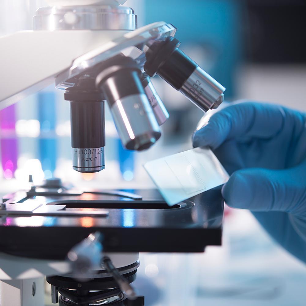 A scientist placing a slide under a microscope