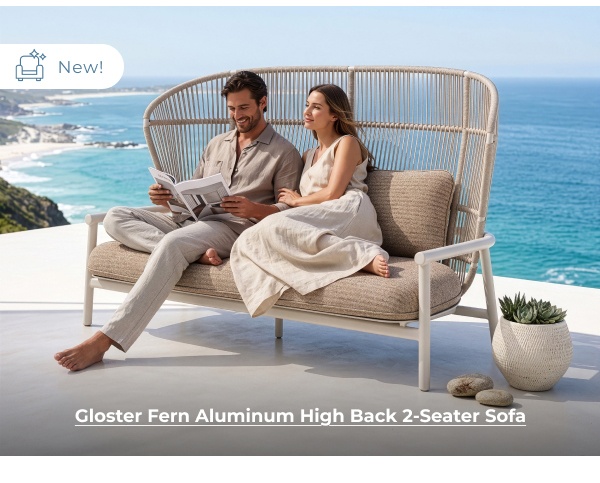 Couple sitting on outdoor high-back daybed. Image Text: New! Gloster Fern Aluminum High Back 2-Seater Sofa