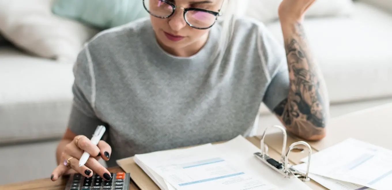 Person calculating expenses with calculator.