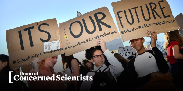 Group of young activists holding signs at a climate protest.