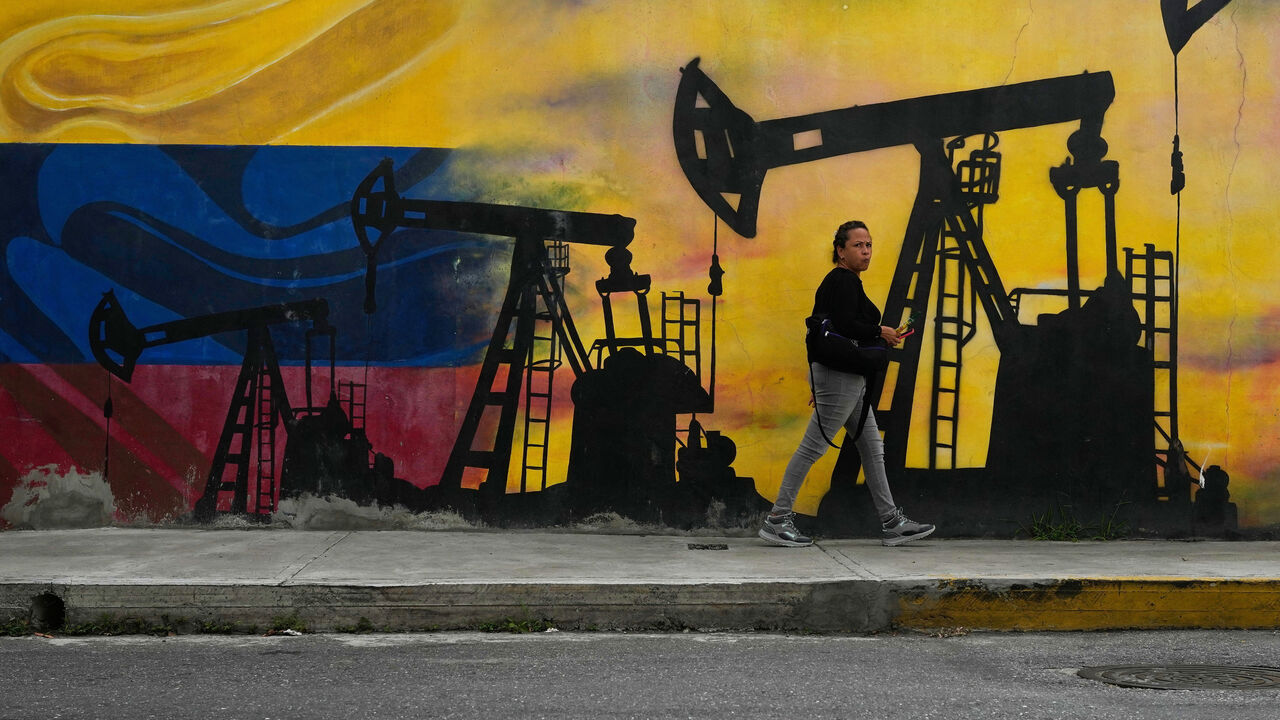 A local walks past a mural featuring oil pumps and wells in Caracas, Venezuela