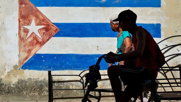 People pass an image of the Cuban flag in central Havana.