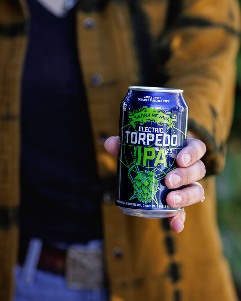A hand holding out a can of Electric Torpedo IPA