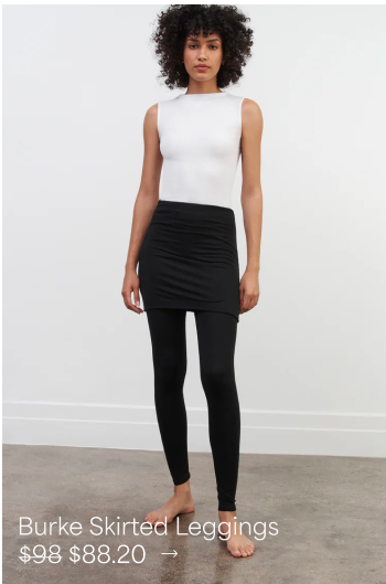 Astrid stands barefoot in The Burke Skirted Leggings and a white sleeveless top against a studio backdrop.