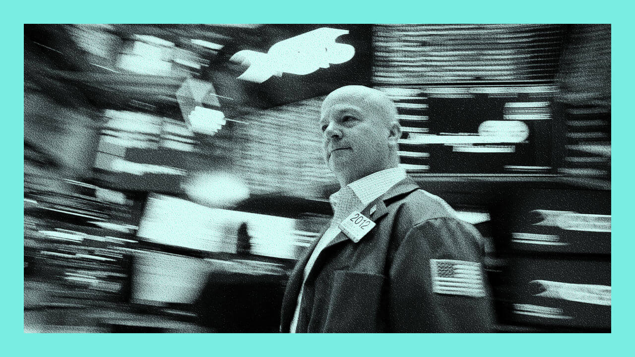 A trader works on the floor of the NYSE in New York - with blurred digital boards in the background.