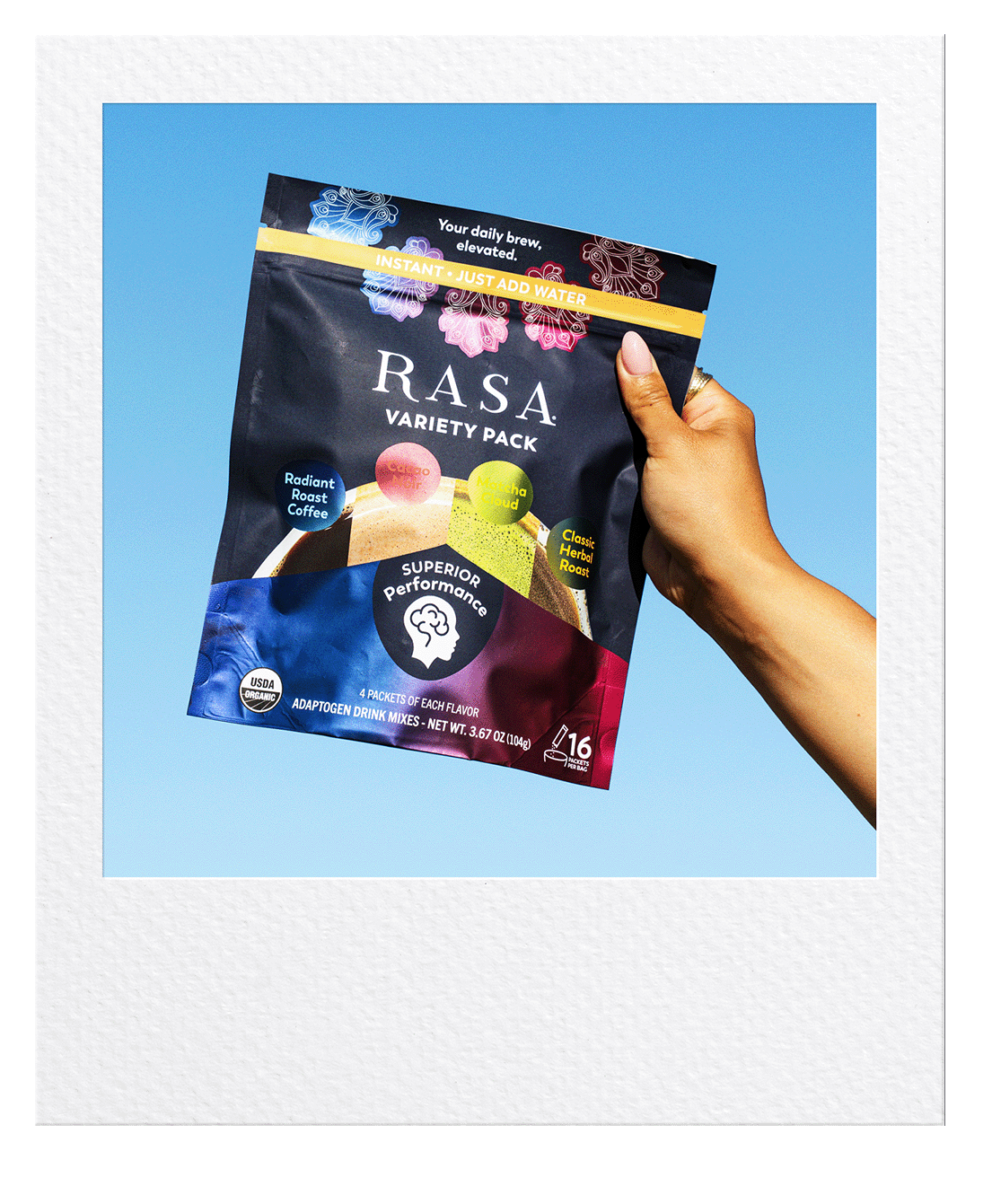 A polaroid picture of a hand holding up the Rasa Variety Pack in the sky. 