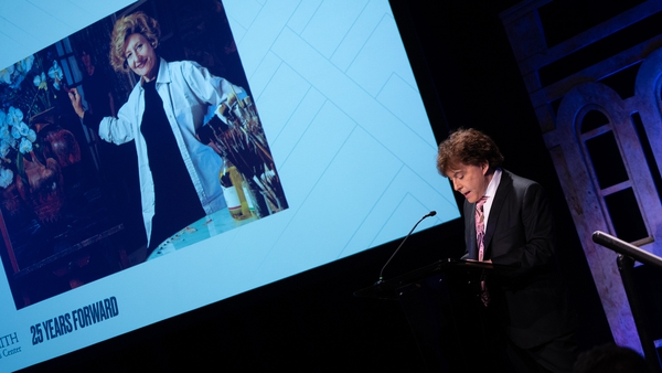 man speaks at podium, with image of Clarice Smith on screen behind him