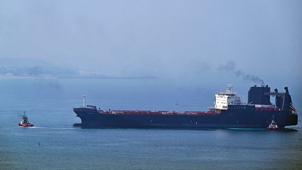 A tugboat guides a ship at the Khor Fakkan Container Terminal in the Gulf of Oman