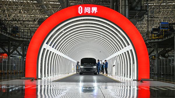 Employees check electric vehicles before they roll off the production line at Seres Super Factory in Chongqing, China