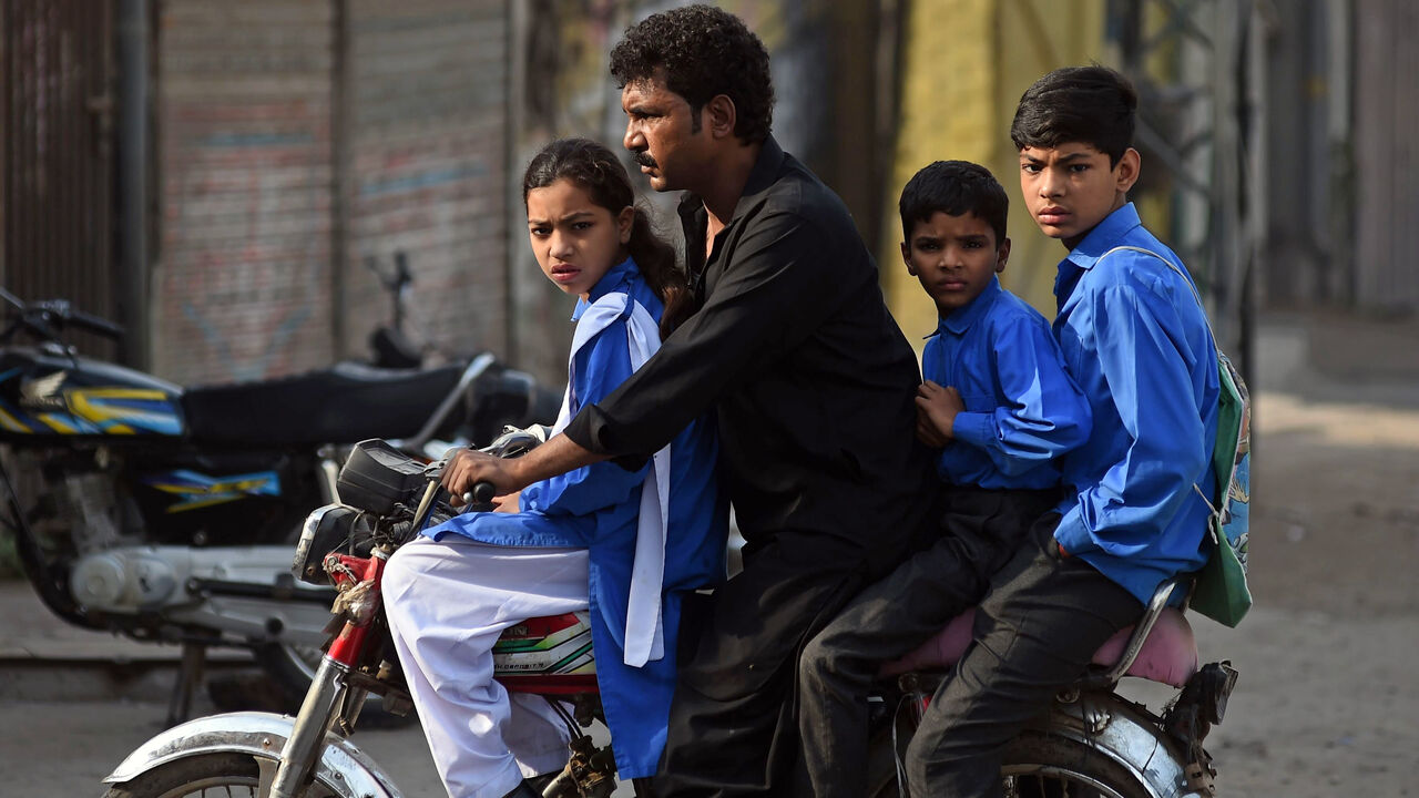 A man takes his children to school on a motorcycle.