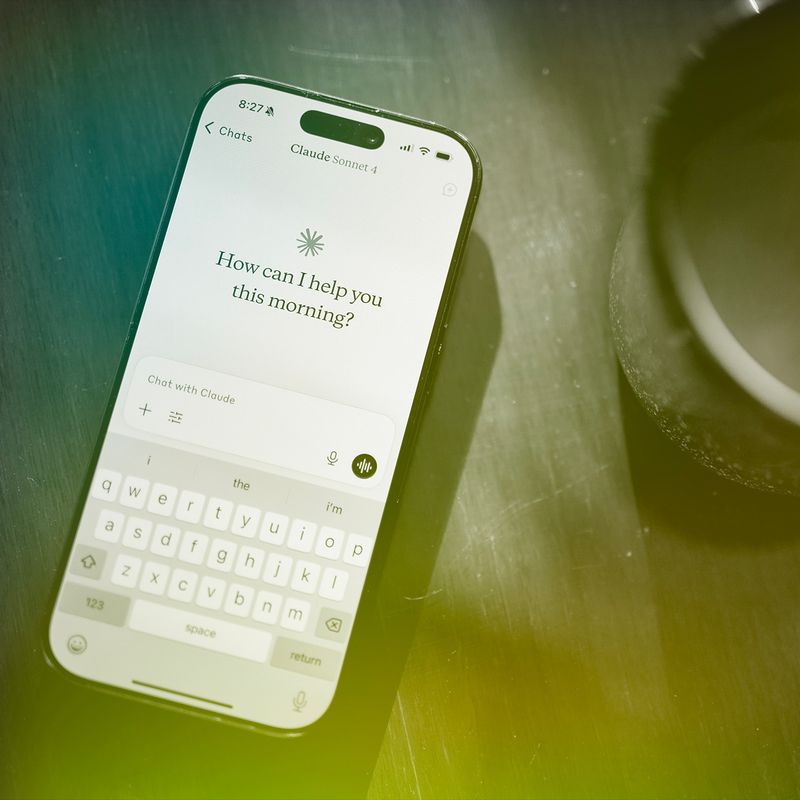 Smartphone with an A.I. app open next to a cup of coffee.