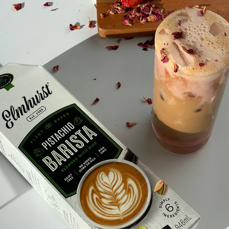 Pistachio Barista Milk with a glass of strawberry rose latte with flower petals. 