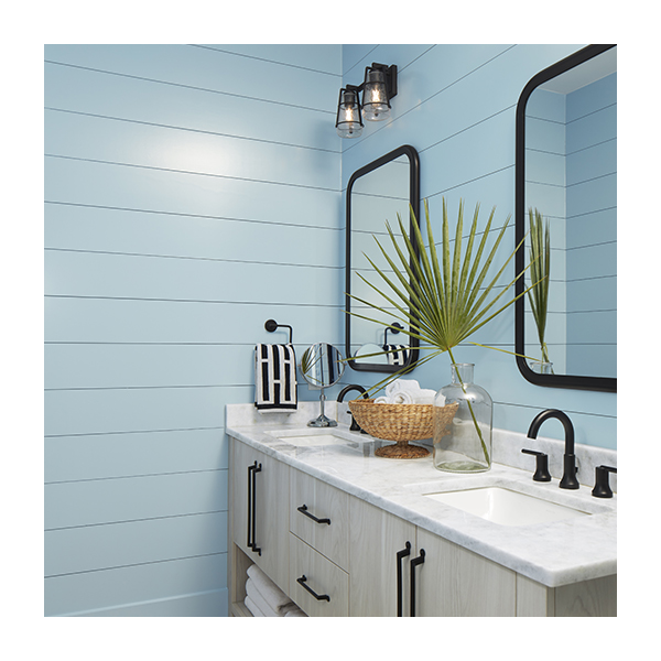 A bathroom with blue painted shiplap walls and a blonde wood double vanity.