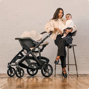 Mom holding baby with her travel system 