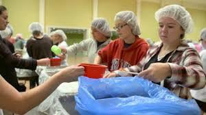volunteers wearing hairnets pack meals