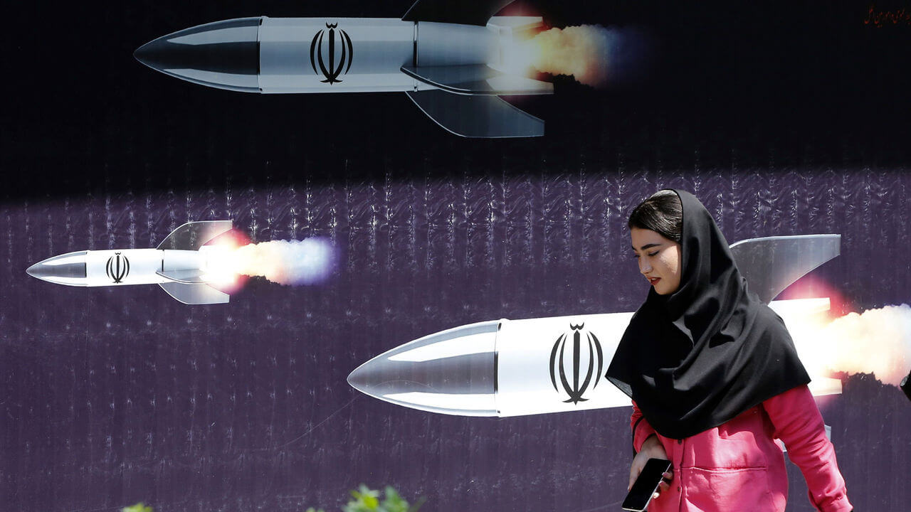 A woman walks past an anti-Israel banner carrying pictures of Iranian missiles in Tehran, Iran