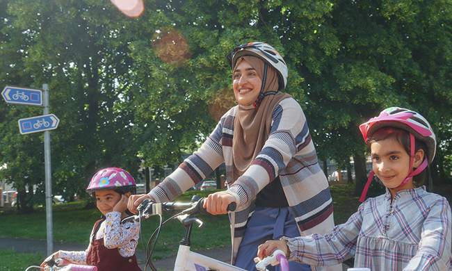 A mother (Sara from the following article) and two of her daughters wearing helmets and getting ready to ride.