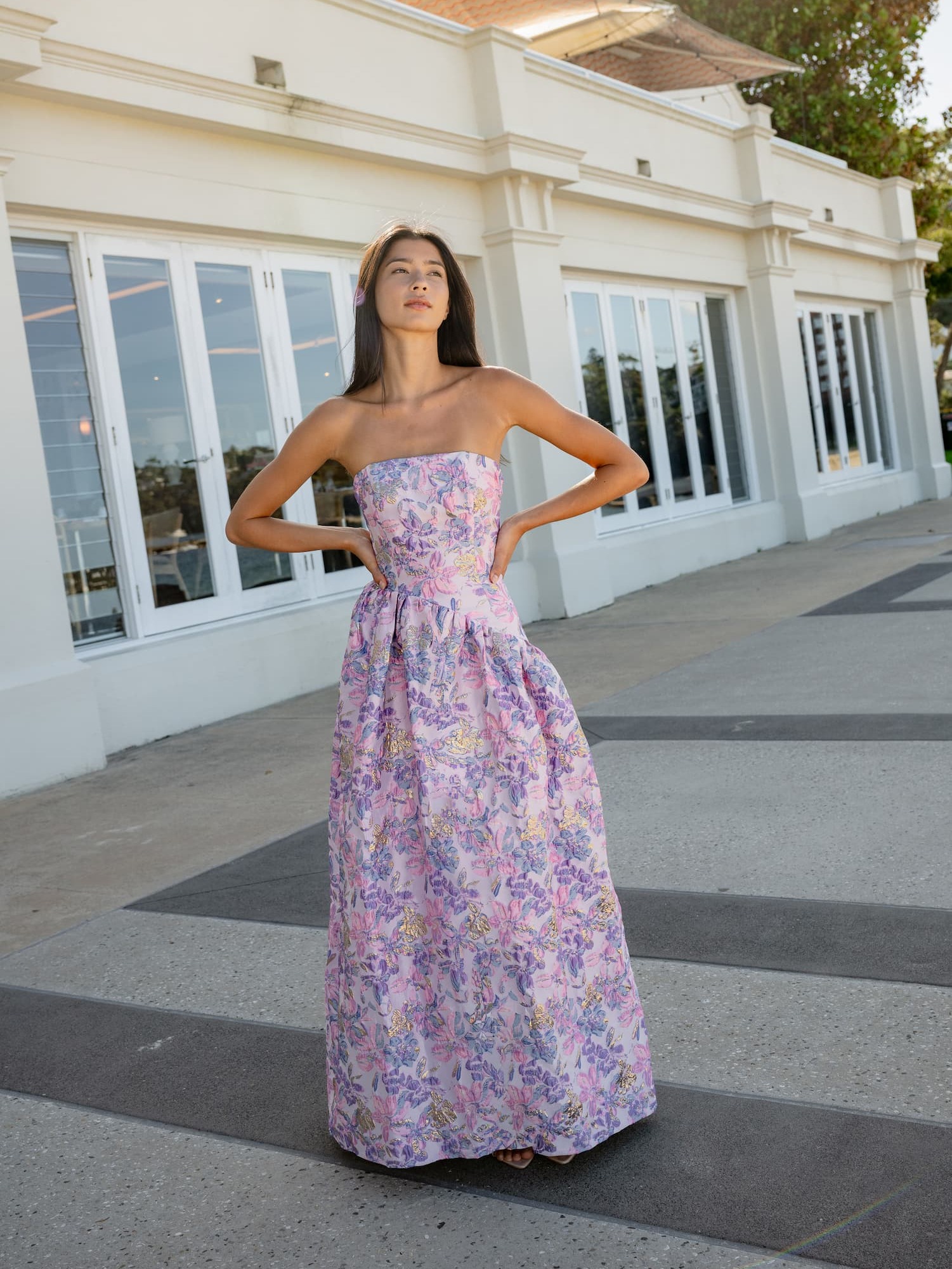 an image of a woman in a dress standing by a pillar