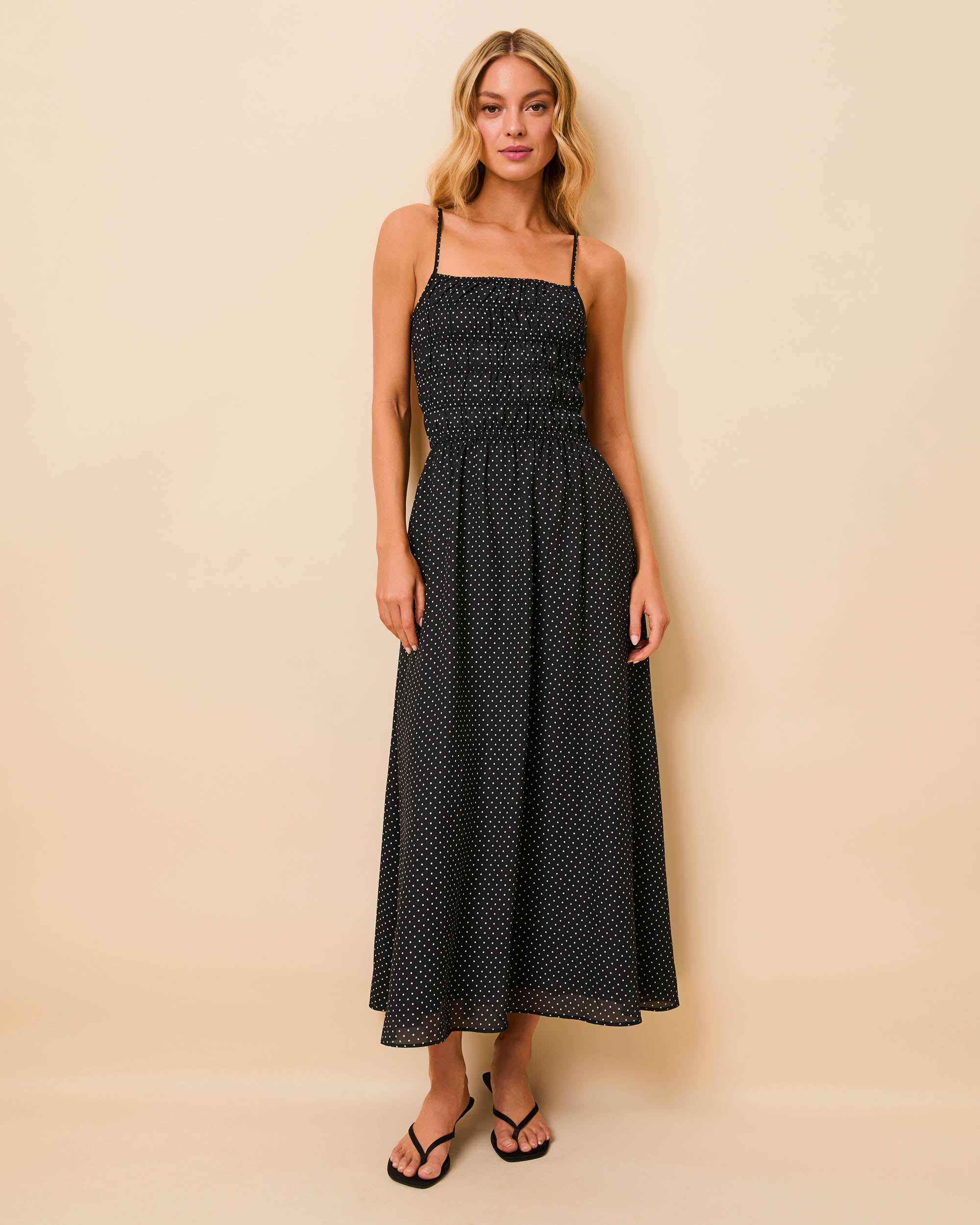 woman in full length black thin strap dress with small white polka dots