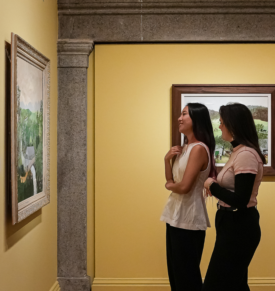 Two women viewing artwork by Grandma Moses in the Smithsonian American Art Museum’s exhibition Grandma Moses: A Good Days Work