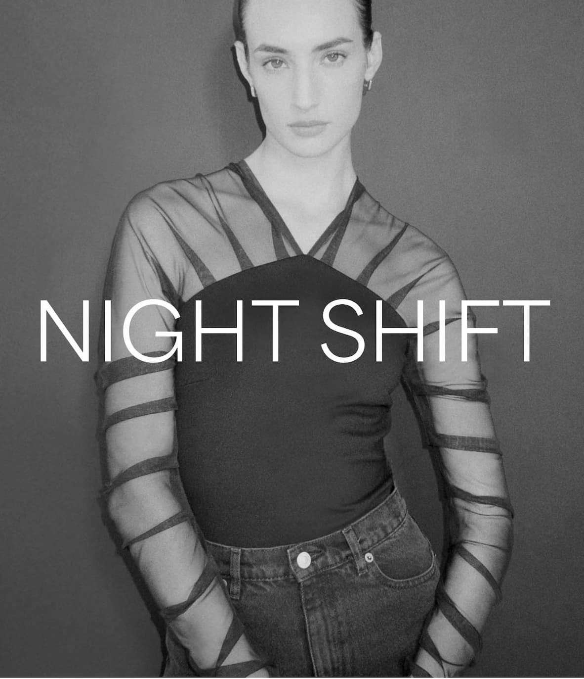 Emily stands in The Lita Top with pleated mesh sleeves and dark denim jeans.