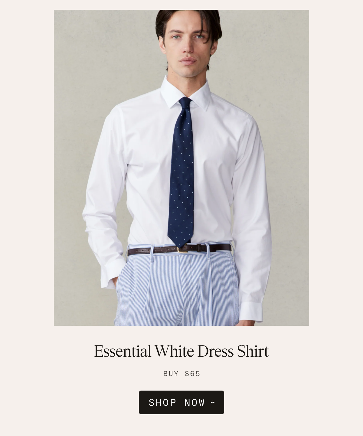 Man wearing the Essential White Dress Shirt with a navy polka dot tie, brown belt, and light blue striped trousers. Text reads: Essential White Dress Shirt. BUY $65. SHOP NOW →
