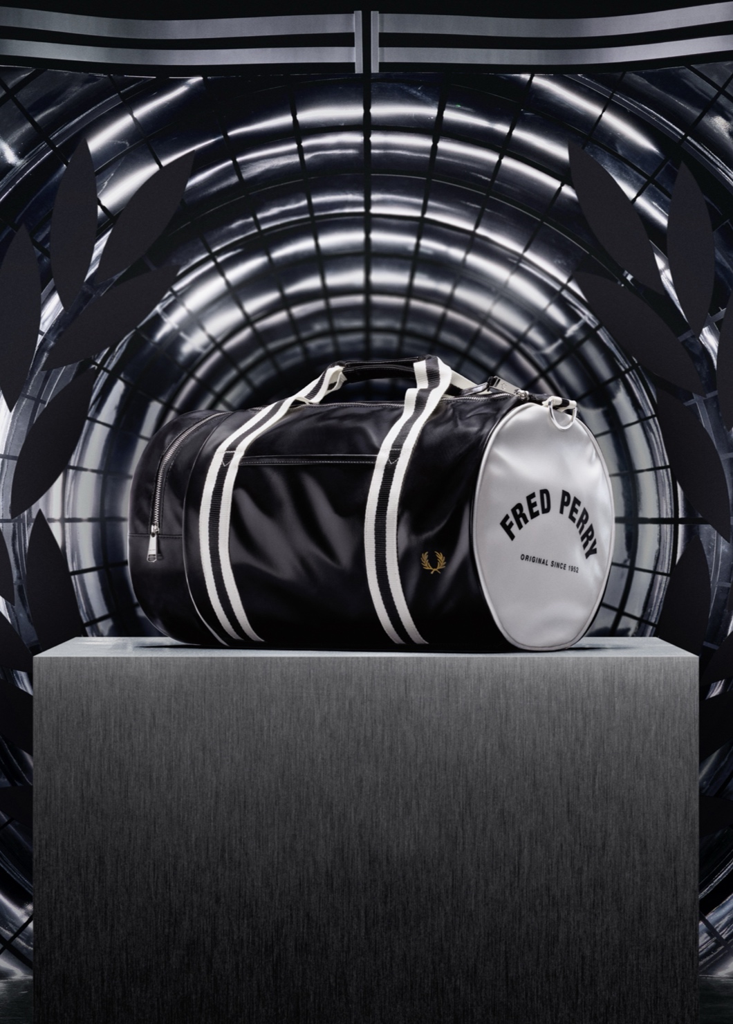 A photograph of our classic black and white barrel bag sitting on top of a podium