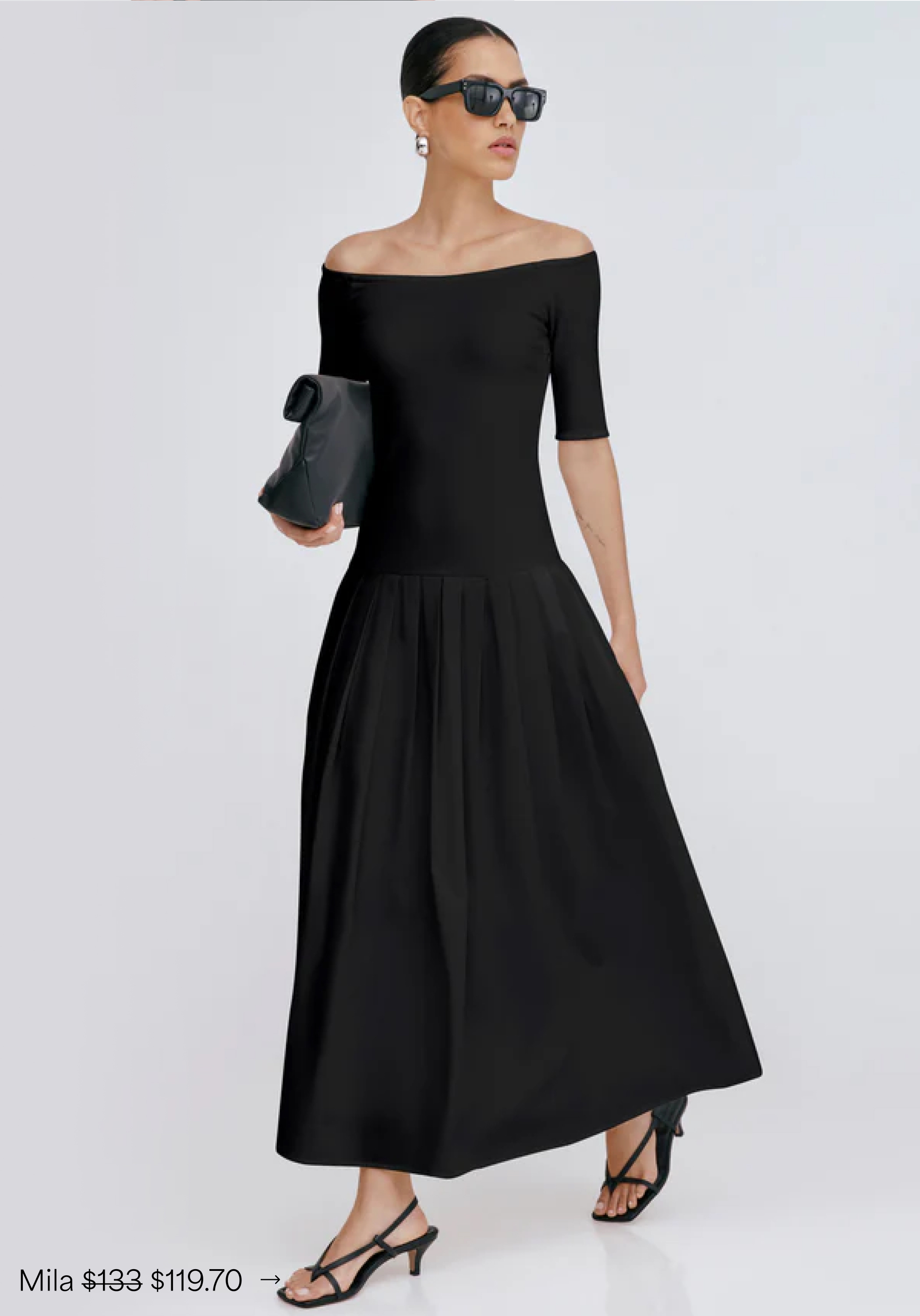 Astrid in The Mila Dress with a fitted bodice and pleated skirt, styled with sunglasses, a clutch, and strappy heels.