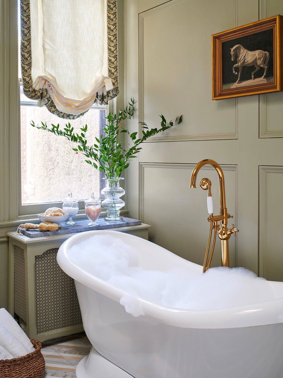 The bath has been run and is ready for you to sink into the bubbles and enjoy the calm and elegant surroundings. The standalone bath has a burnished gold central tap and shower, meaning no arguments over who gets the tap end. The pale green walls make peaceful backdrop to the collection of elegant glass jars and historic painting of horse. A space made to linger in.