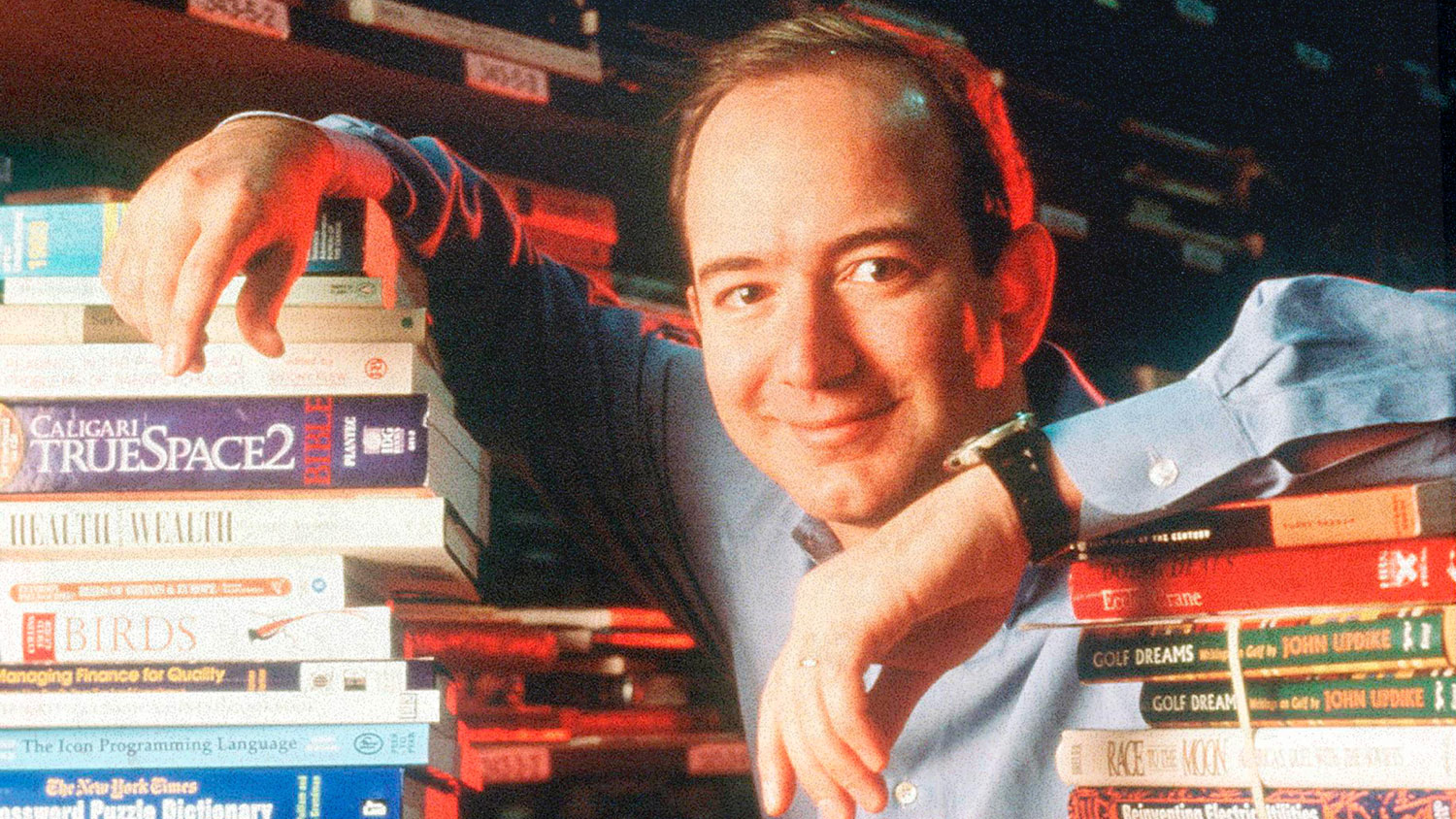 A man poses with piles of books.