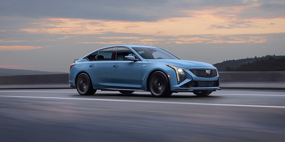 Light blue CT5-V driving on a road at dusk.
