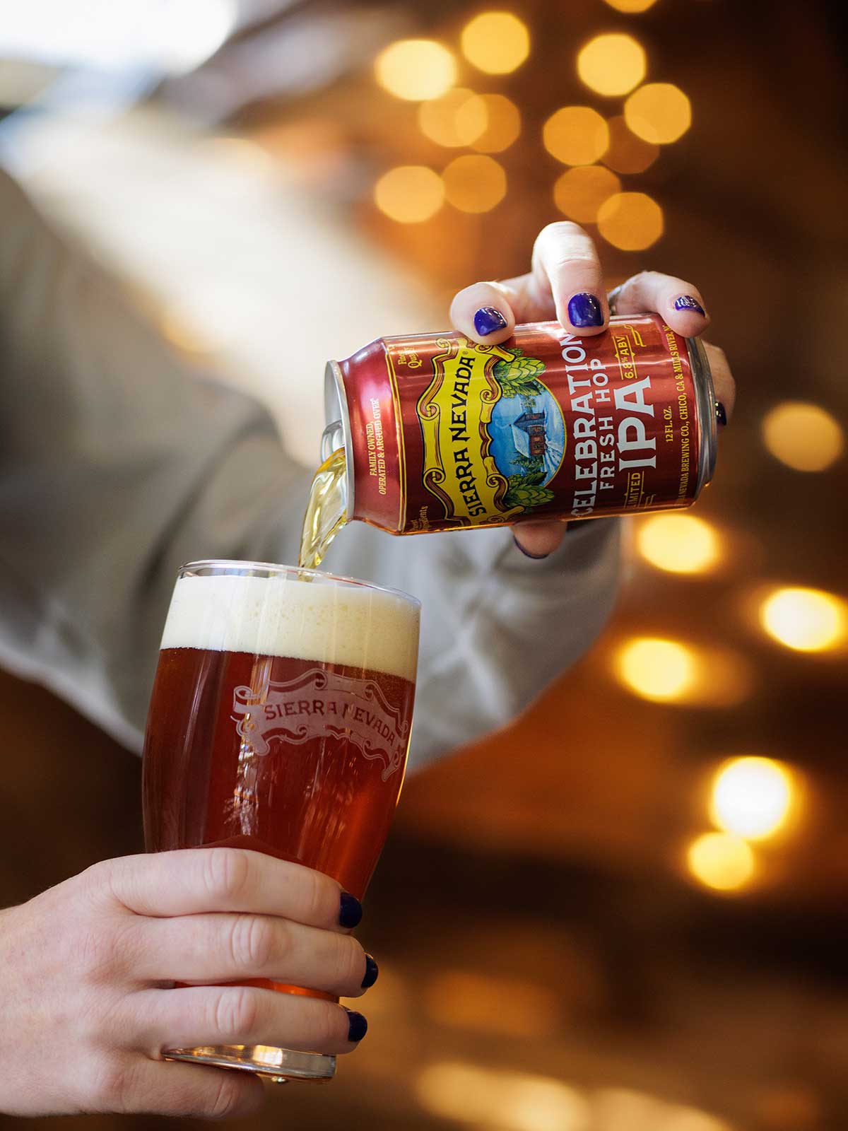 Hands pouring a can of Celebration IPA into a glass