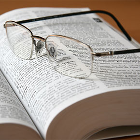 A pair of glasses on a dictionary.