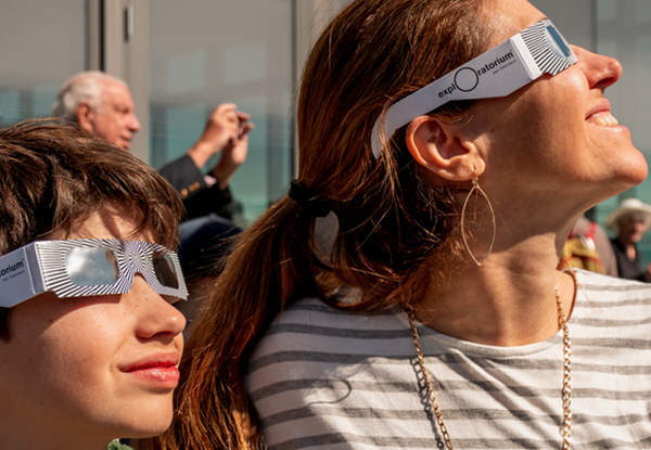 A woman and her son looking at an eclipse.