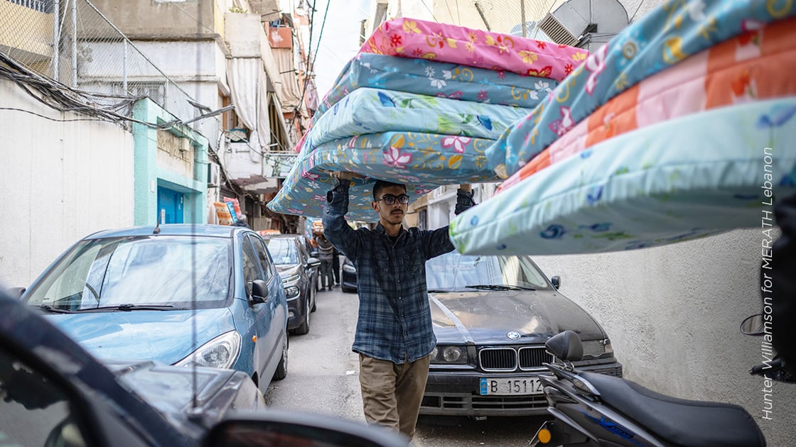 Man in Middle East carrying mattresses.