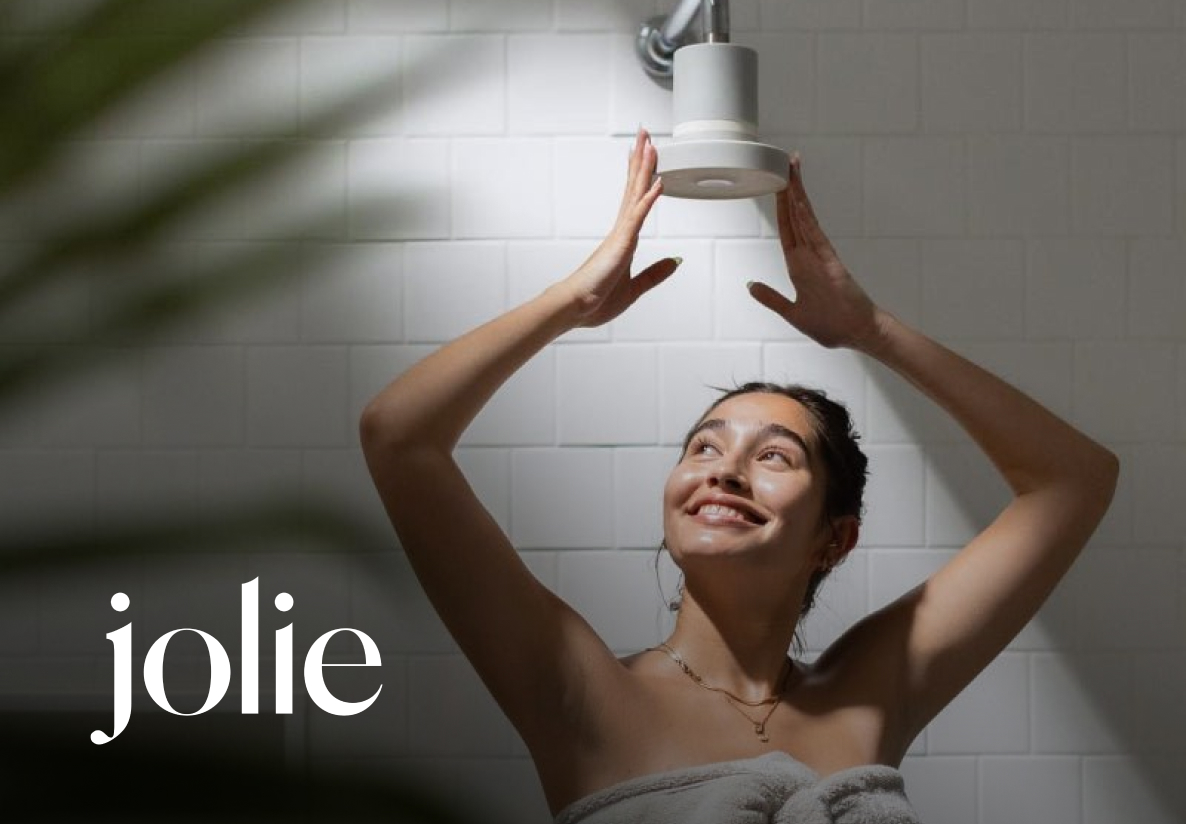 Woman standing underneath Jolie shower head