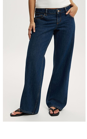 Woman wearing dark blue wide-leg jeans with a white top and black slides