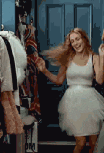 Yada in The Drea Top with sheer drape walks confidently beside a GIF of Carrie Bradshaw dancing in a white tank top and tutu.