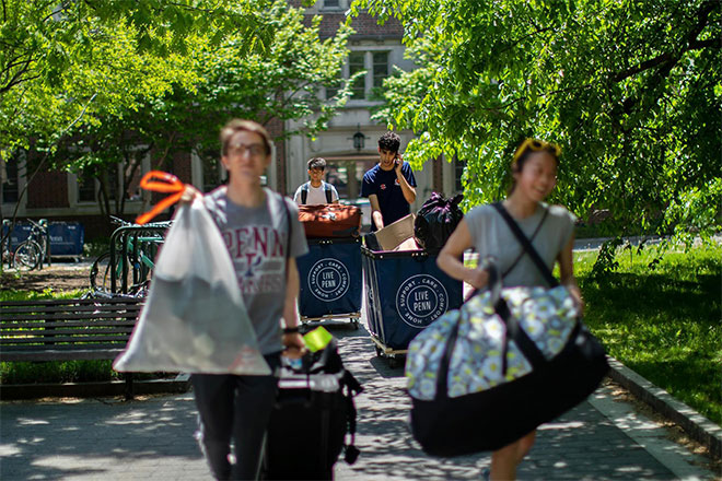 Students carry luggage and push carts on Move-Out day.